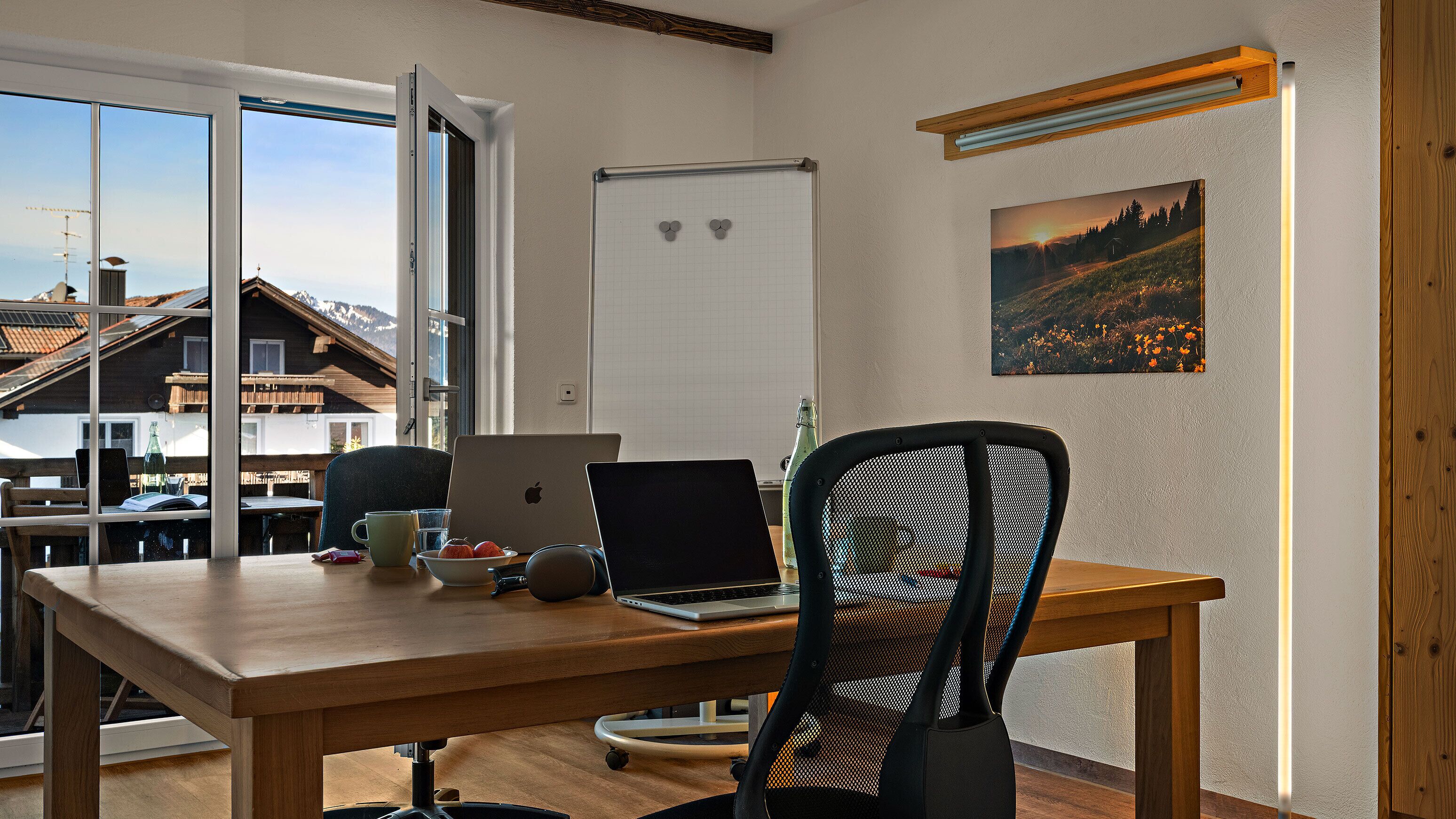 Una habitación moderna con una mesa de madera, una computadora portátil, una silla y una botella.