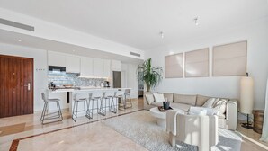 A modern living room with a sofa, coffee table, and bar stools. - Apartment 'Paraiso Pueblo' with Sea View, Wi-Fi and Air Conditioning (Benahavís)