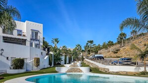 A modern pool area with a clear blue pool, white buildings, and palm trees. - Apartment 'Paraiso Pueblo' with Sea View, Wi-Fi and Air Conditioning (Benahavís)