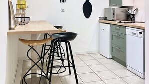 Eine moderne Küche mit einem Holztisch, schwarzen Hocker, einer Mikrowelle und einem Geschirrspüler.