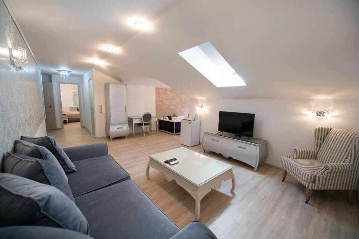 Un loft moderno con tragaluces, una sala de estar con sofá, mesa de centro, televisión y un sillón a rayas.