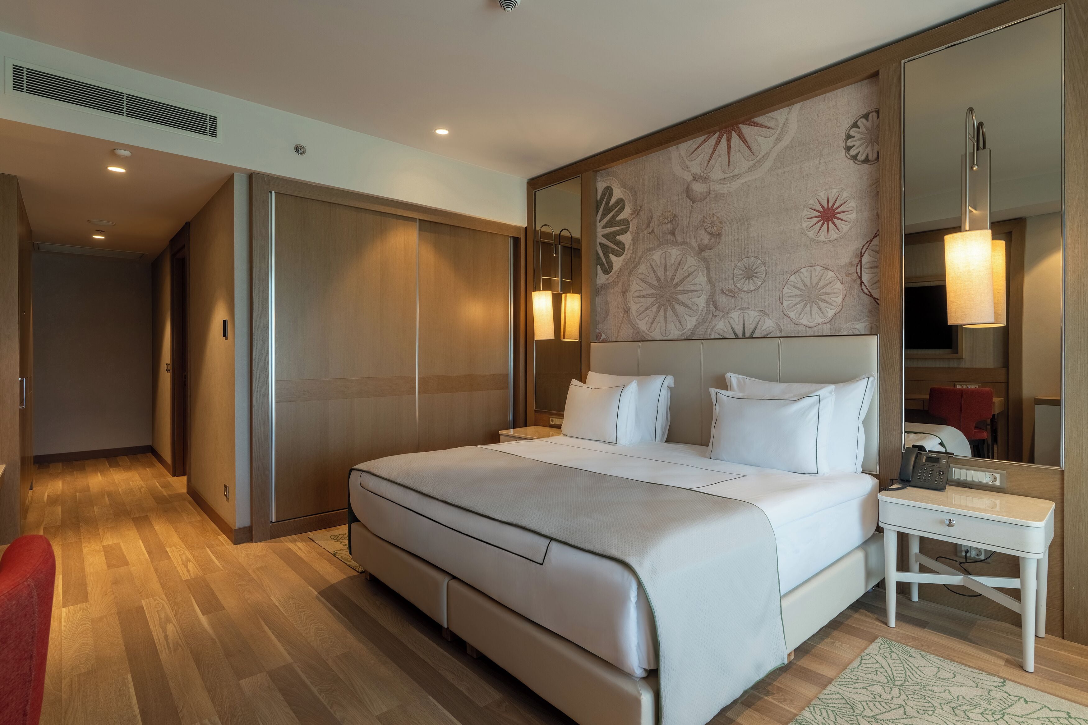 Habitación de hotel con una cama grande, una mesita de noche, un espejo y un armario.