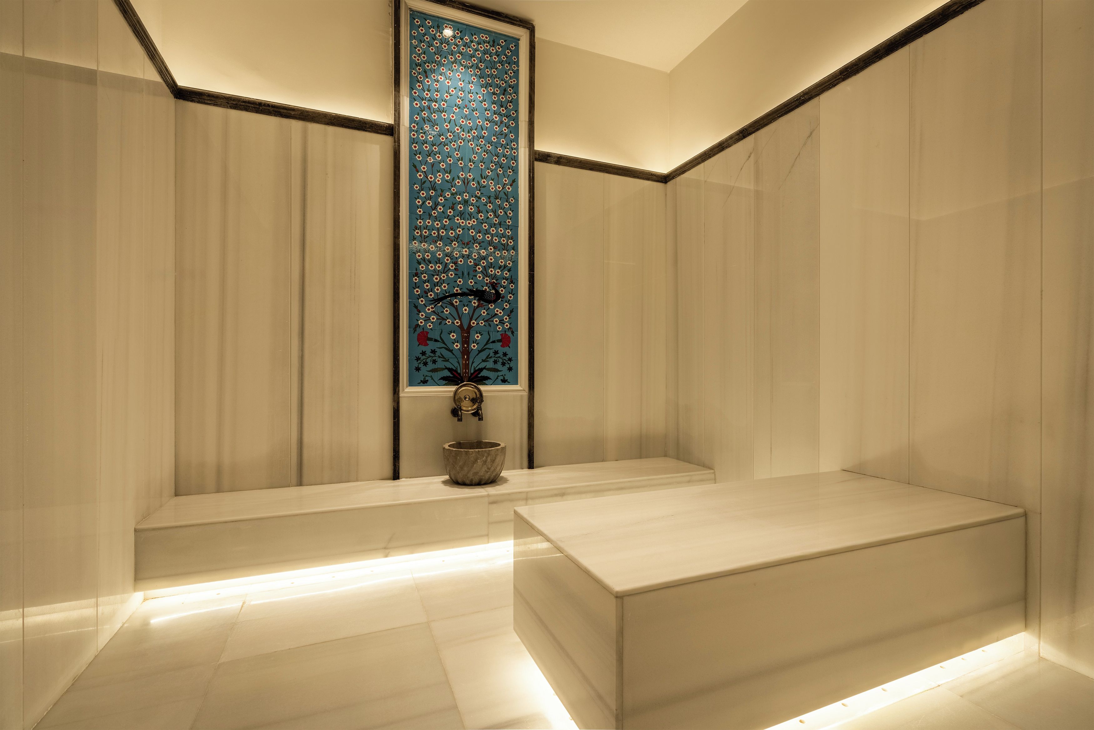 A modern bathroom with a large mirror, a sink, and a decorative wall panel.