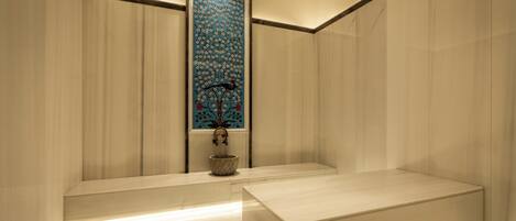 A modern bathroom with a large mirror, a sink, and a decorative wall panel.