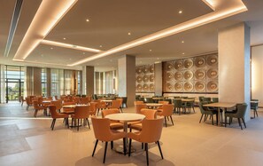 A spacious indoor area with multiple tables and chairs, large windows, and a wall with circular patterns. - Sinnada Resort & Thermaland (Afyonkarahisar)