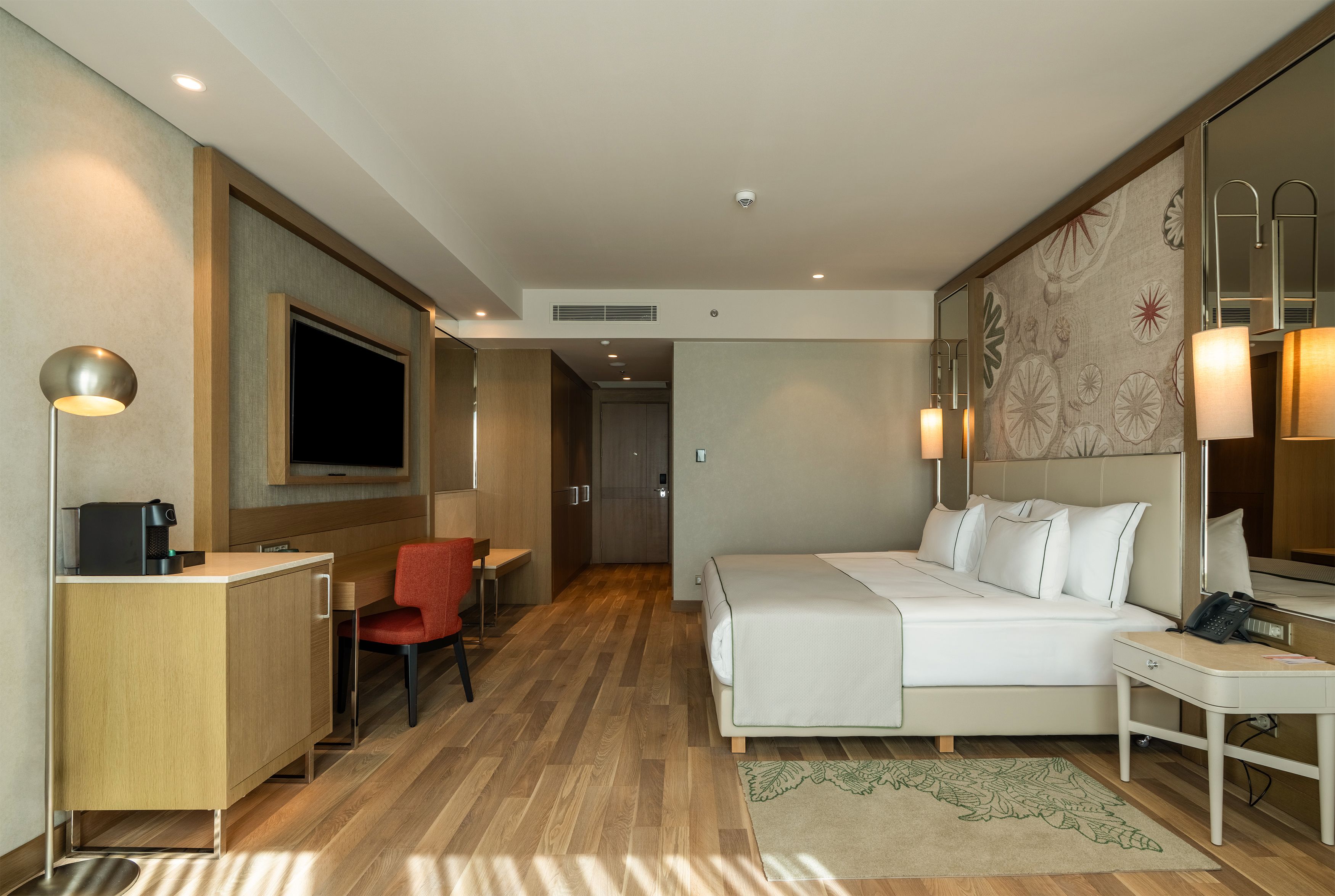 Habitación de hotel con cama, escritorio, silla y televisor.