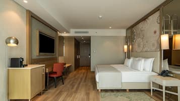 Habitación de hotel con cama, escritorio, silla y televisor.