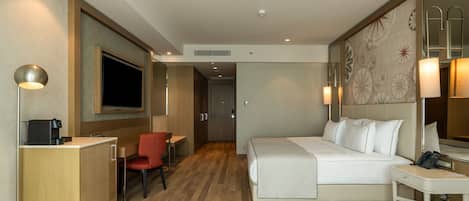 Habitación de hotel con cama, escritorio, silla y televisor.
