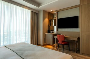 A hotel room with a bed, a desk with a chair, a television, and a window with curtains. - Sinnada Resort & Thermaland (Afyonkarahisar)