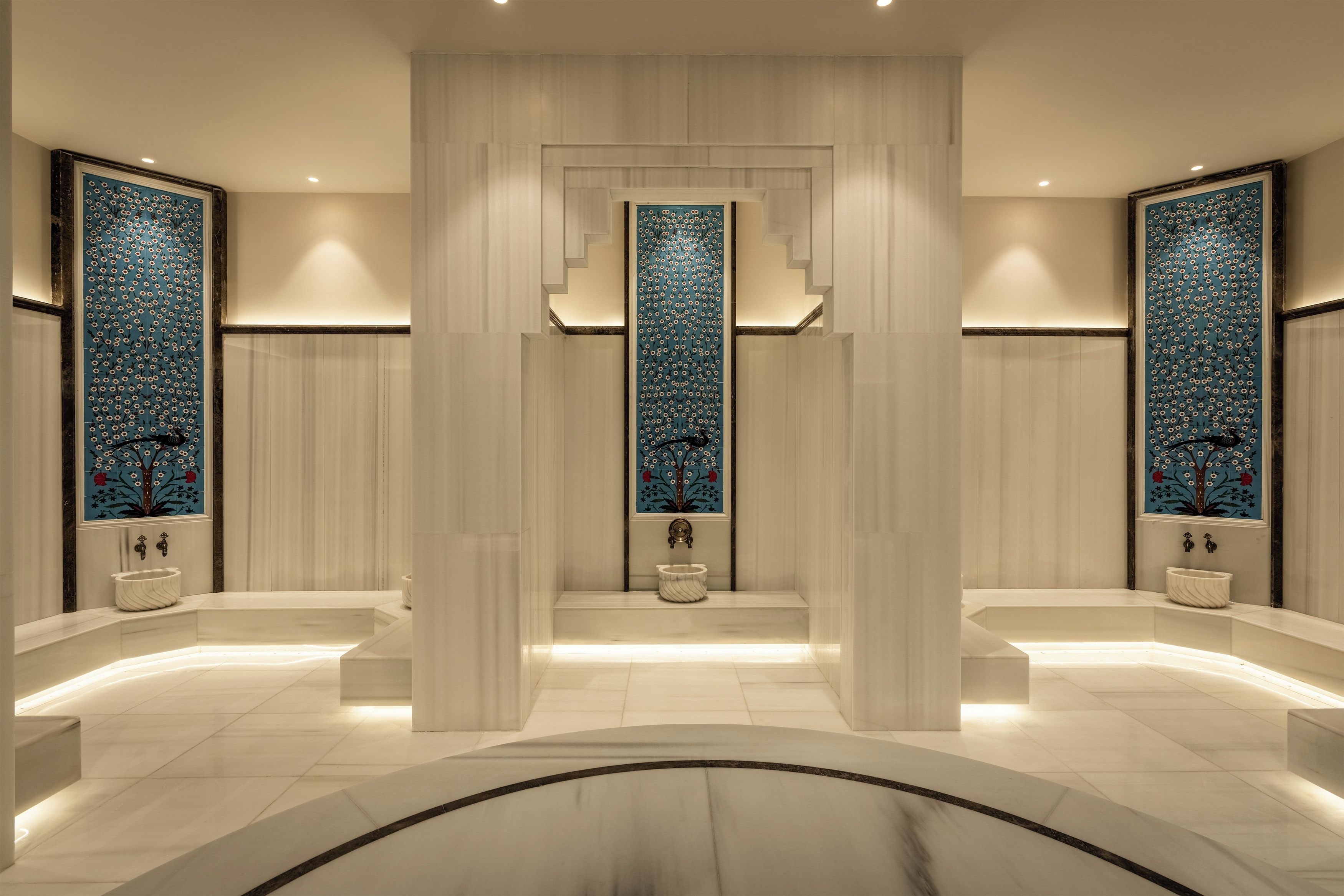Un baño moderno con un pilar central, dos lavamanos y azulejos decorativos.