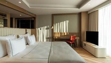 Habitación de hotel con una cama grande, un escritorio, una silla, un televisor y un armario.