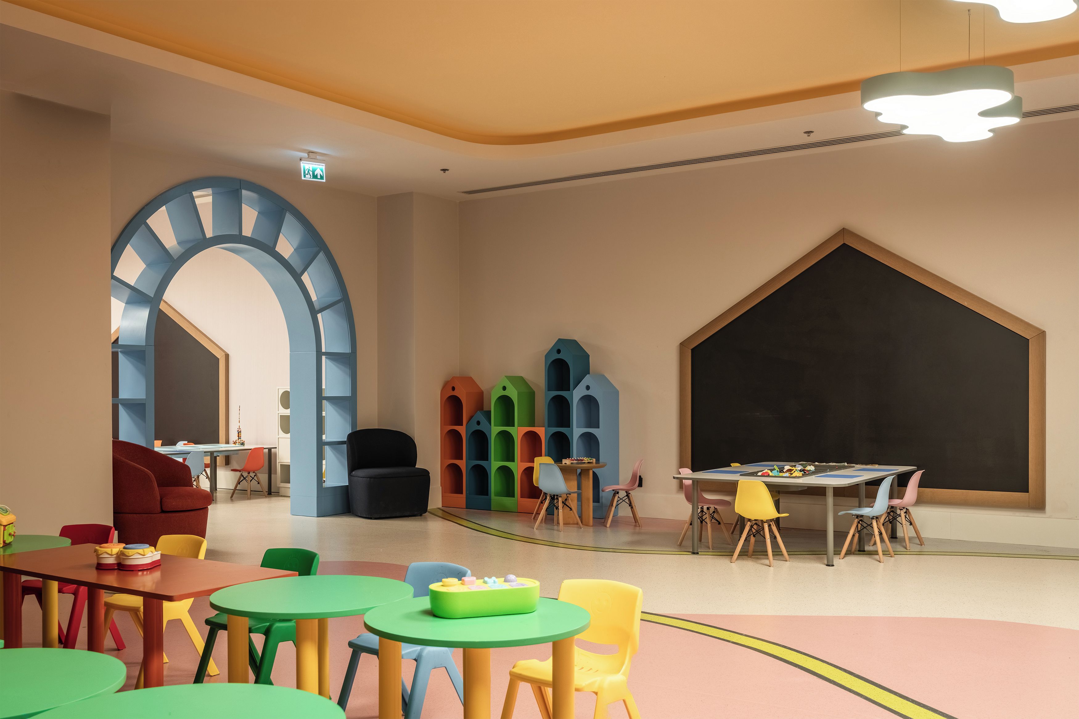 Un salón infantil con muebles coloridos y una pared con pizarra.