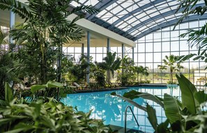 An indoor swimming pool with a glass ceiling, surrounded by lush tropical plants. - Sinnada Resort & Thermaland (Afyonkarahisar)