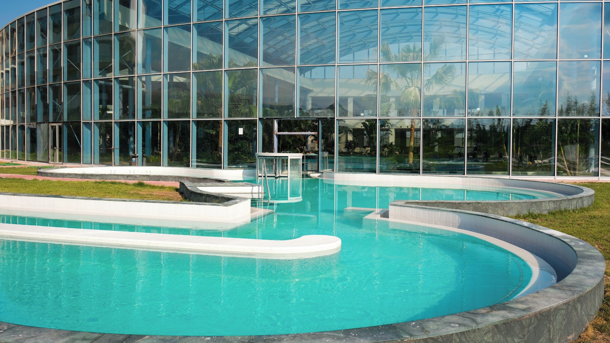 Un edificio moderno con amplios ventanales y una piscina central.