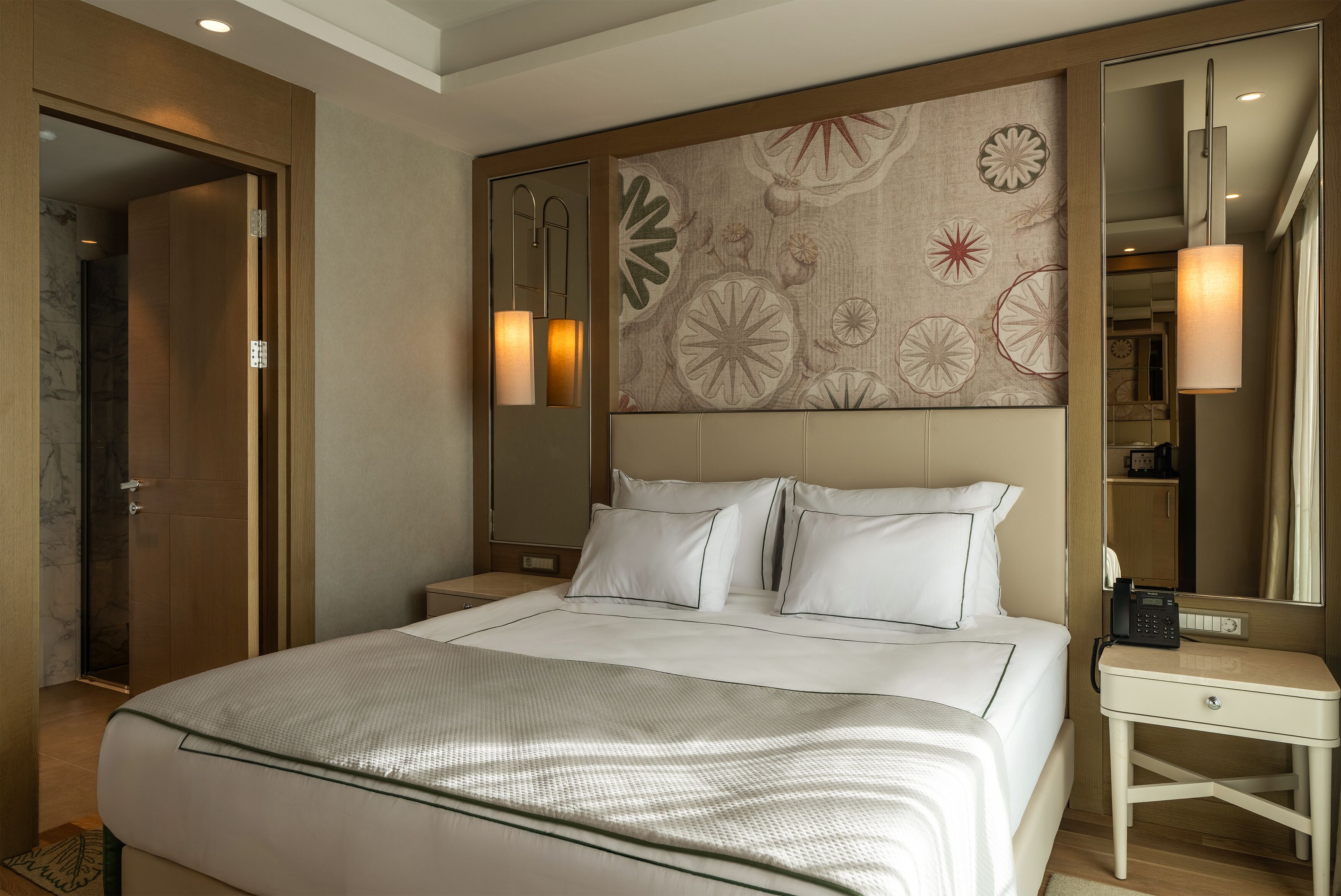 Una habitación de hotel con una cama grande, una mesita de noche, una lámpara de pared y un espejo.