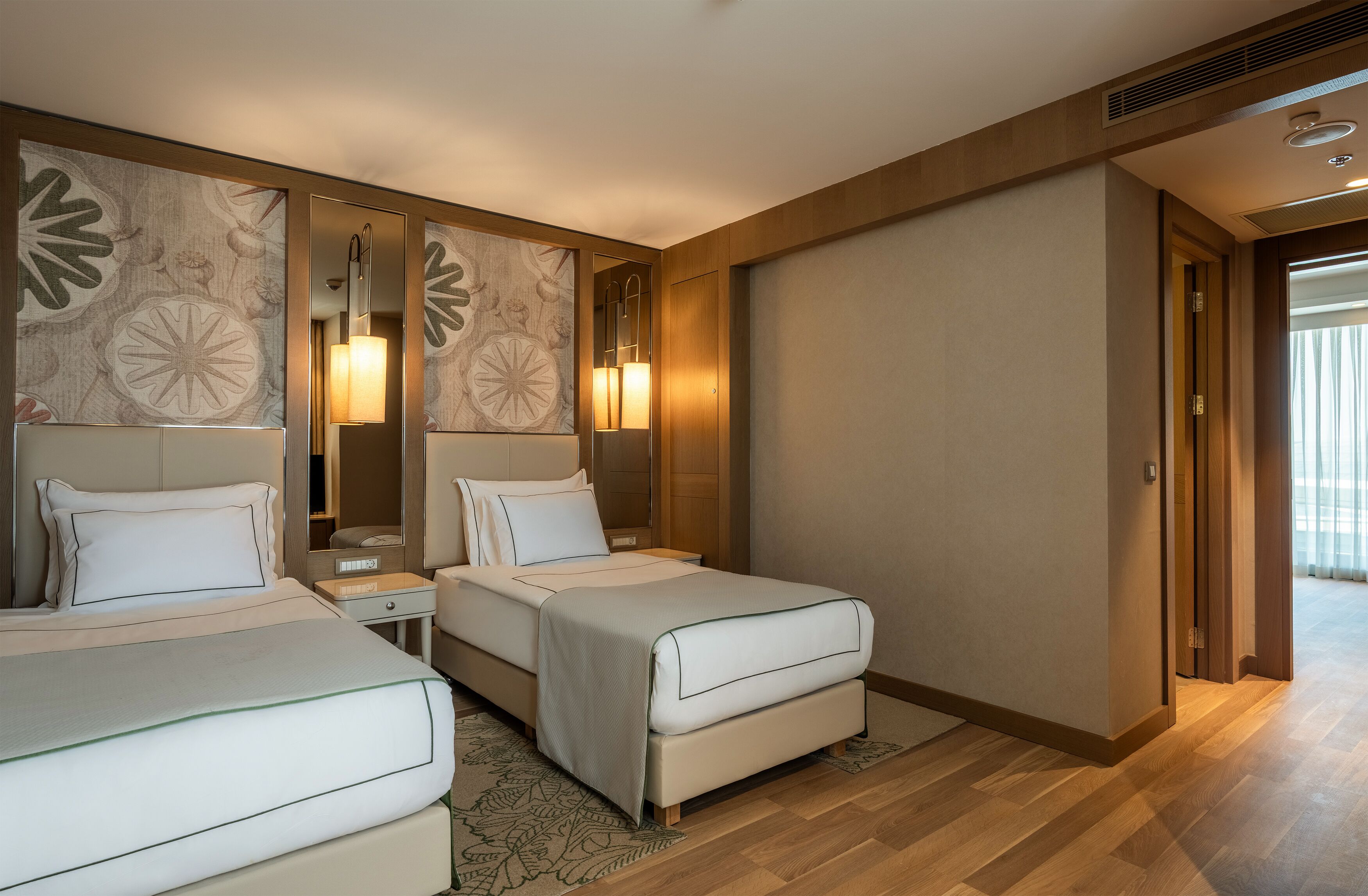 A hotel room with two beds, a large mirror, and a view of the outside.