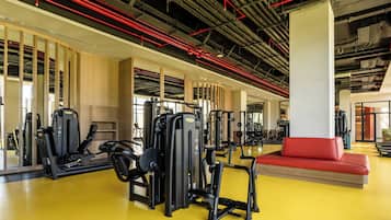 A gym with exercise equipment, a red couch, and a yellow floor.