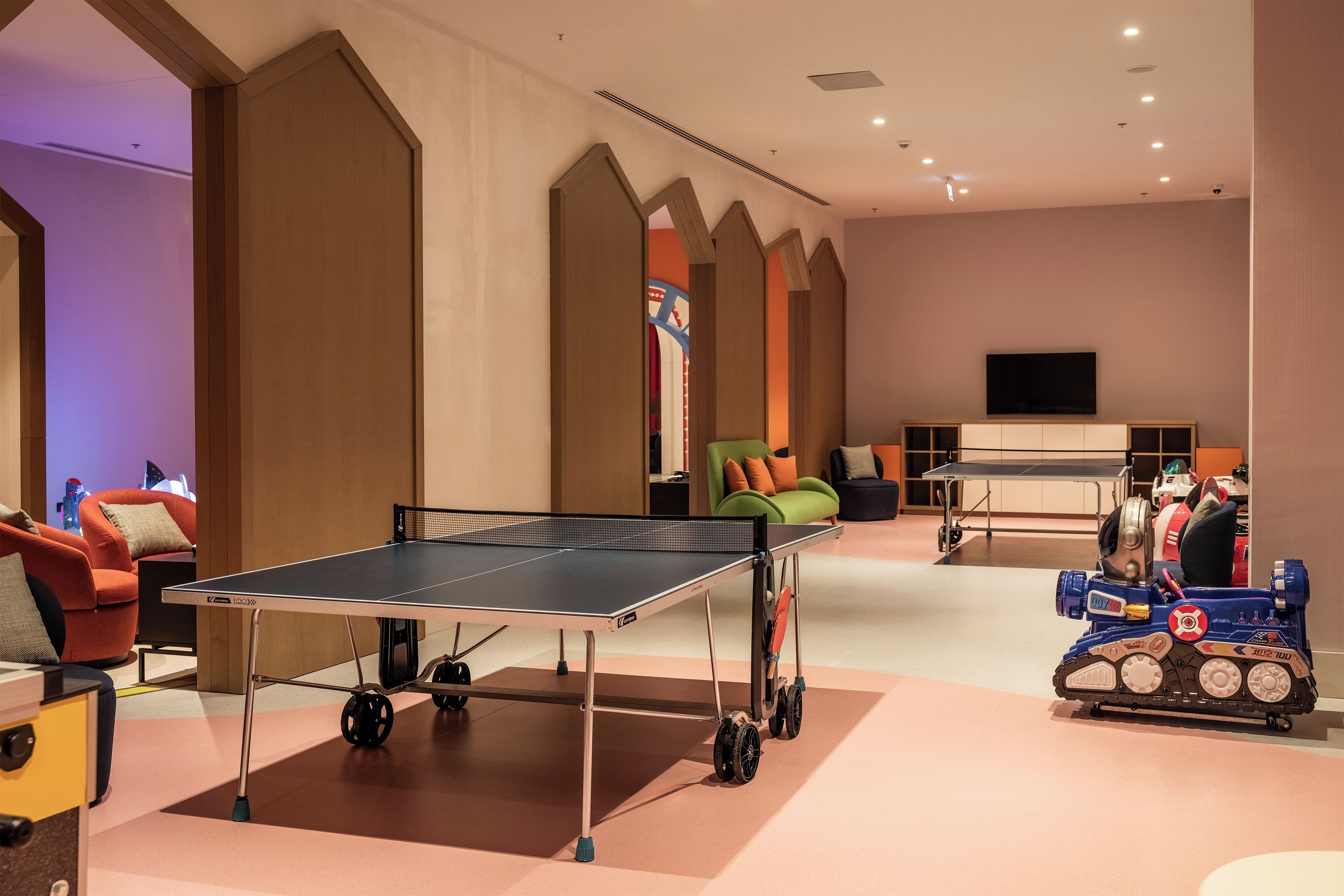 A room with a ping pong table, a robot, and a sofa.