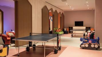A room with a ping pong table, a robot, and a sofa.