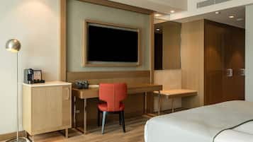 A hotel room with a bed, a desk, a chair, a television, and a wardrobe.