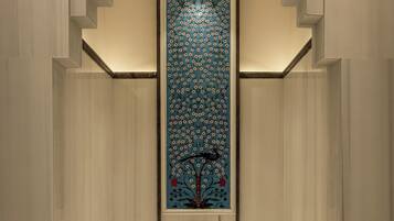 A modern bathroom with a marble floor, a sink, and a decorative wall panel.