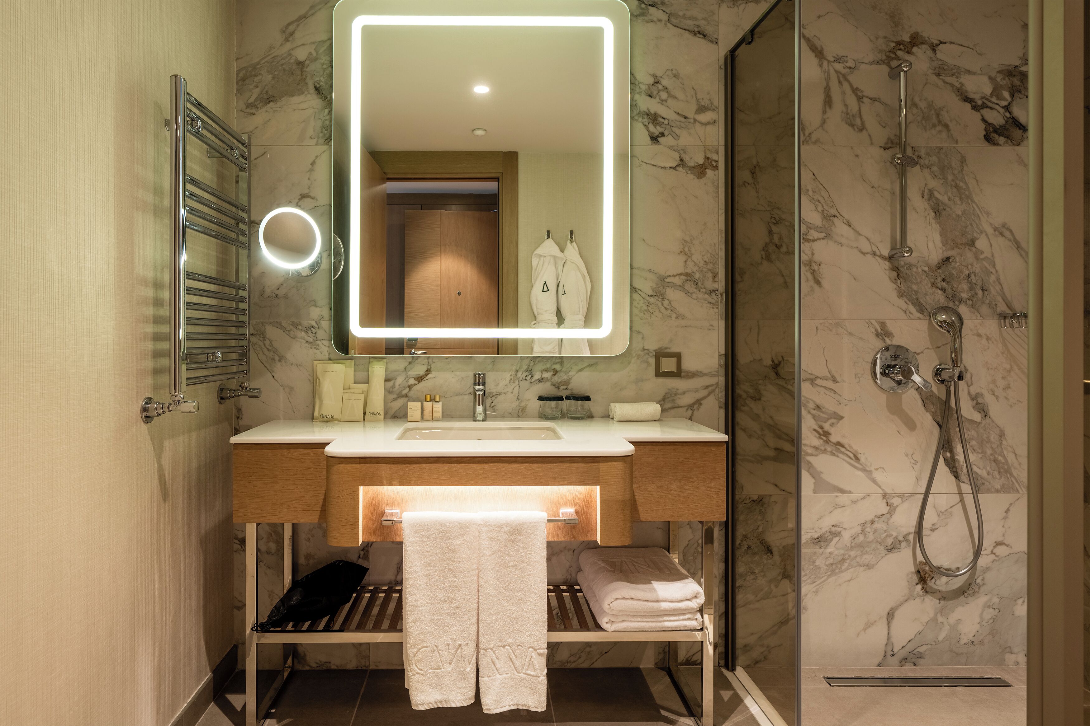 A modern bathroom with a vanity, a mirror, a towel rack, and a shower area.
