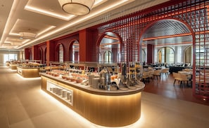 A modern hotel lobby with a central buffet area, seating arrangements, and a decorative red lattice structure. - Sinnada Resort & Thermaland (Afyonkarahisar)