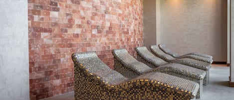 A spa area with a brick wall and a seating area with mosaic-patterned loungers.