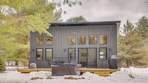 Een modern vakantiehuis met grote ramen, een terras en een hottub, gelegen in een besneeuwd landschap.