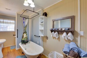 Un baño con bañera, cortina de ducha, toallero y repisa con toallas.