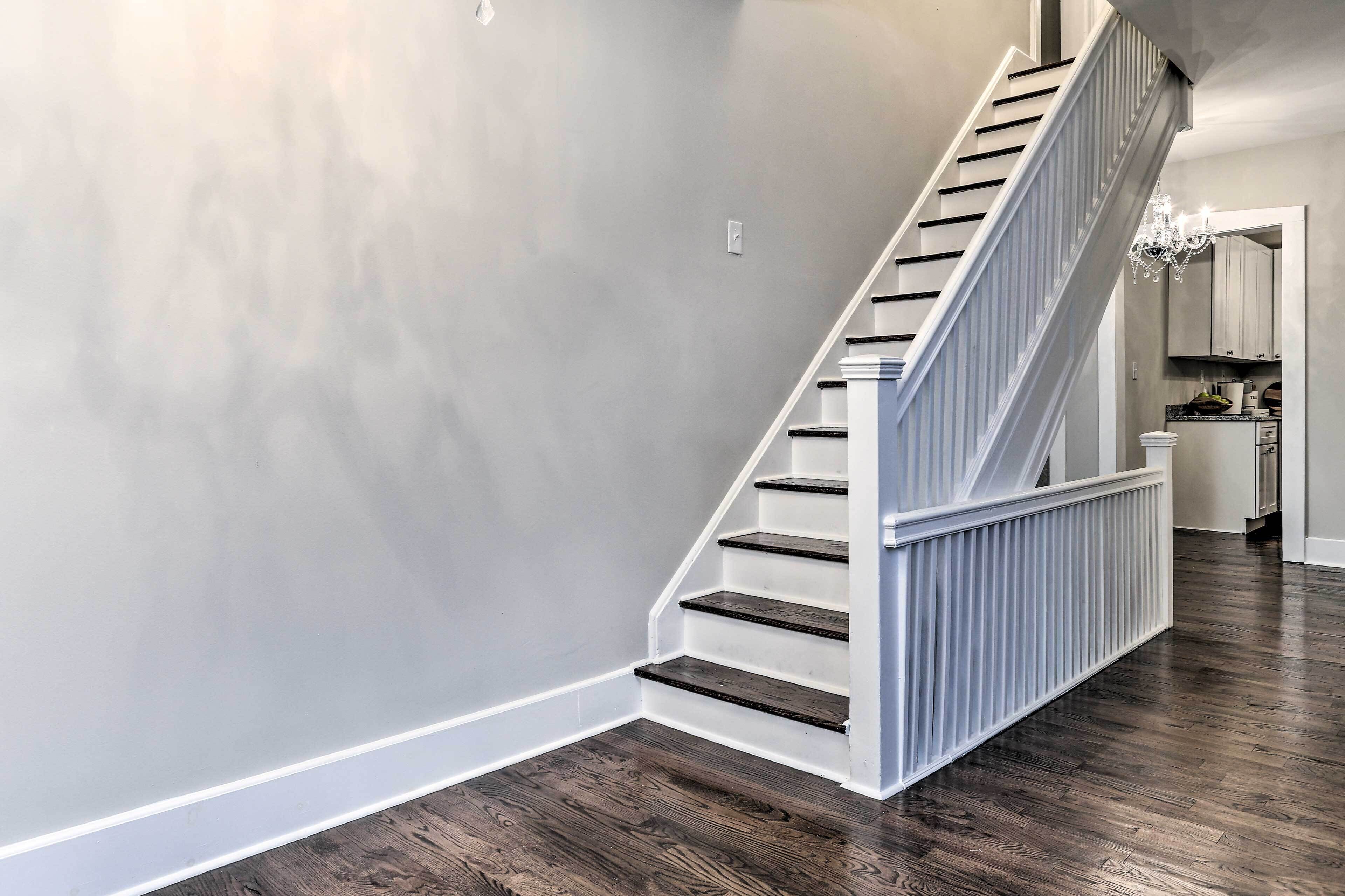 A staircase with white railings and dark wooden steps leading to a kitchen area.