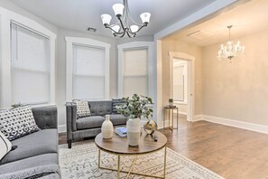 Ein Wohnzimmer mit grauem Sofa, einem runden Couchtisch und einer Deckenleuchte.