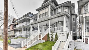 A row of two-story houses with front porches, white railings, and a brick foundation. - Pet-friendly Newark Townhome Near Airport! (Newark)