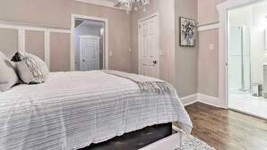 A bedroom with a large bed, a chandelier, a door, and a glass shower area. - Pet-friendly Newark Townhome Near Airport! (Newark)