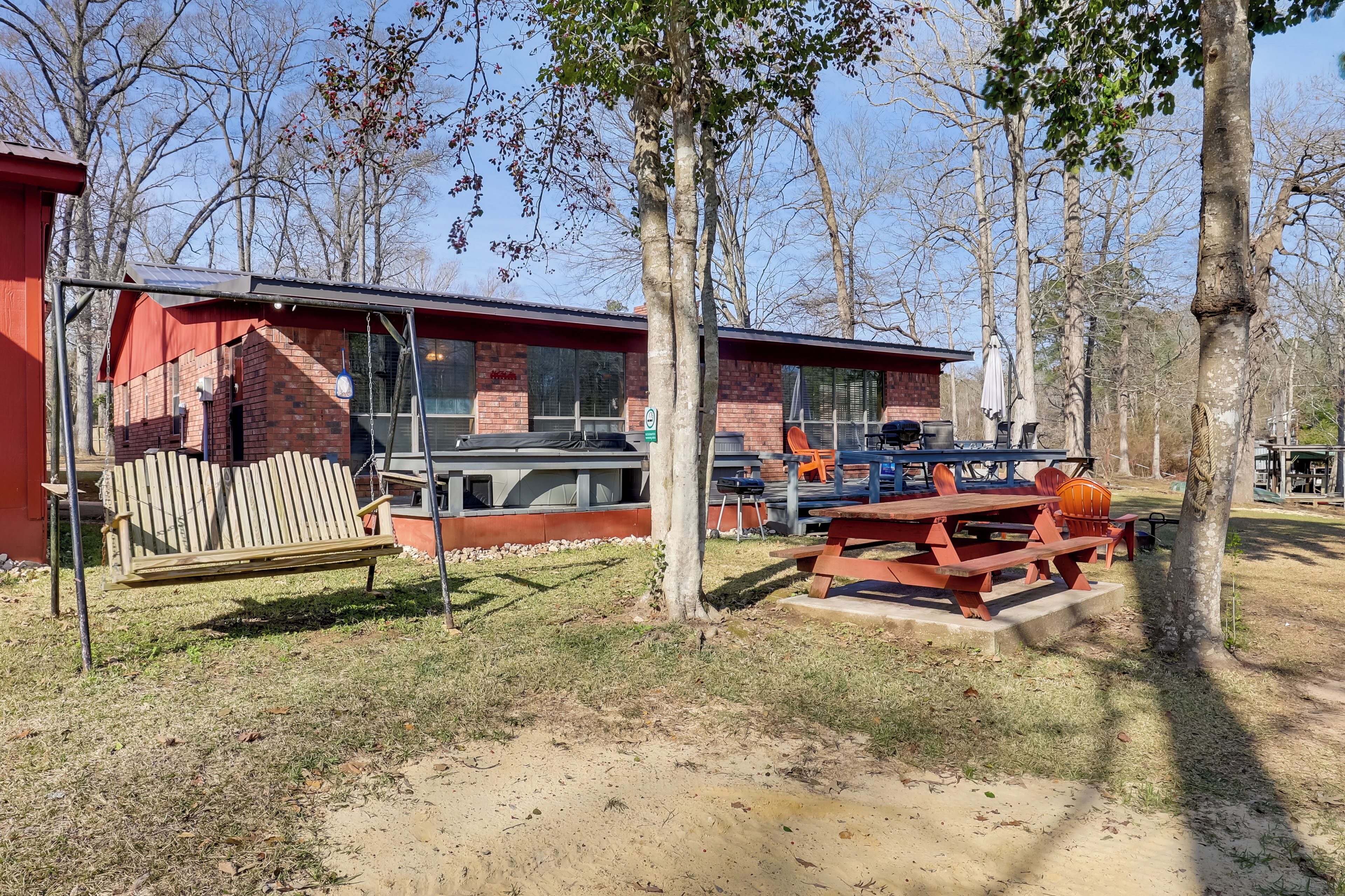 A rustic cabin with a brick exterior, a wooden bench, and a picnic table with outdoor seating.