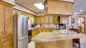 Una cocina con armarios de madera, un refrigerador de acero inoxidable, una encimera de granito y una cafetera.