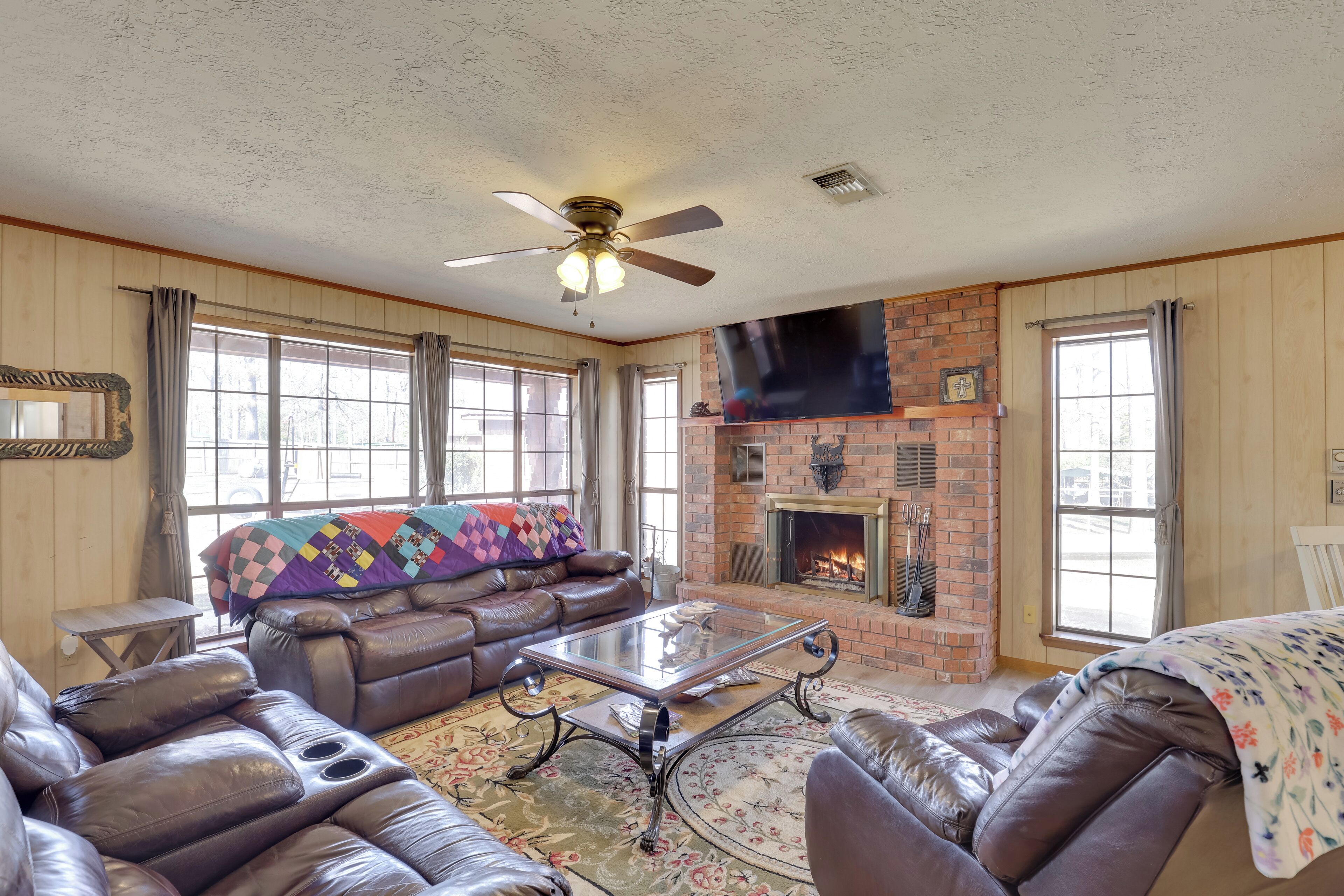 A cozy living room with a leather sofa, a glass coffee table, and a fireplace.
