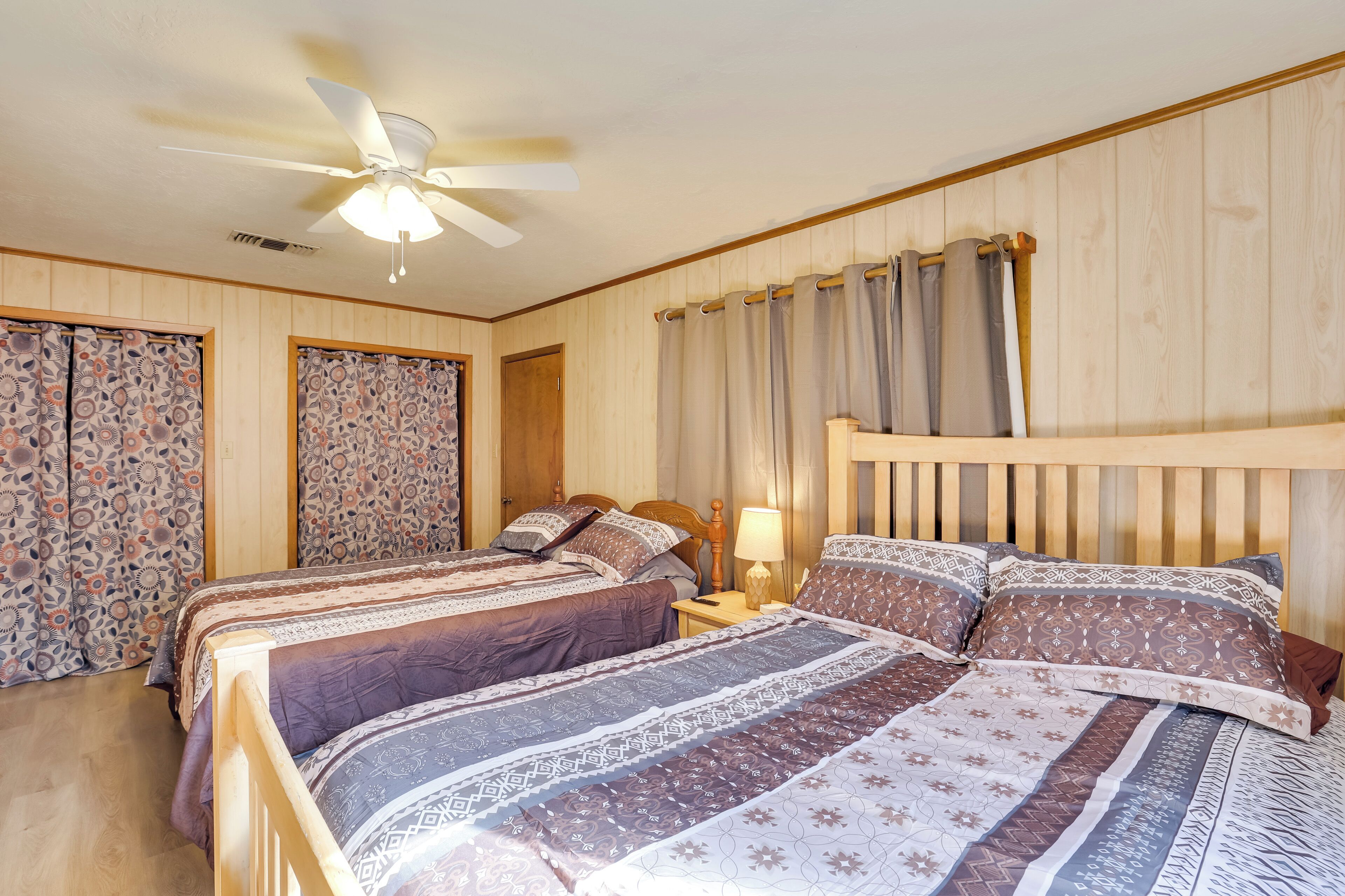 A bedroom with two beds, a ceiling fan, and curtains.