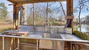 An outdoor kitchen with a sink, wooden deck, and a view of a lake. - Great for Fishing! Lakefront Studio in Hemphill (Hemphill)