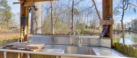 An outdoor kitchen with a sink, wooden deck, and a view of a lake.