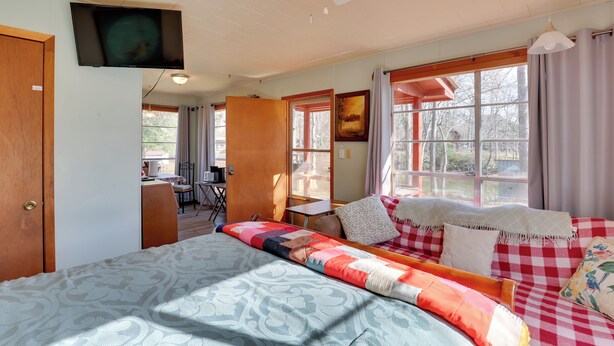A cozy bedroom with a large bed, a desk, and a window with curtains. - Great for Fishing! Lakefront Studio in Hemphill (Hemphill)