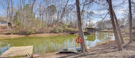 A tranquil lakeside setting with a wooden dock, a lifebuoy, and a small boat.