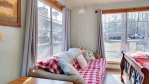 A cozy room with a checkered sofa, a wooden table, and a bed with a patterned bedspread. - Great for Fishing! Lakefront Studio in Hemphill (Hemphill)