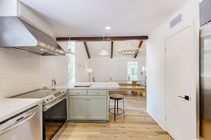 A modern kitchen with a central island, built-in oven, and stainless steel range hood.
