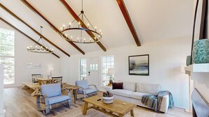 A spacious living room with a wooden coffee table, blue armchairs, a white sofa, and a fireplace. - Modern Treehouse Vibes Close to Club and Lake (Brookeland)