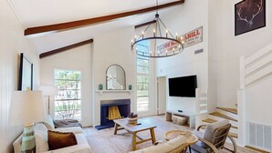 A spacious living room with a fireplace, a chandelier, and a large TV. - Modern Treehouse Vibes Close to Club and Lake (Brookeland)