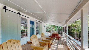 A covered porch with wooden Adirondack chairs and a picnic table. - Modern Treehouse Vibes Close to Club and Lake (Brookeland)