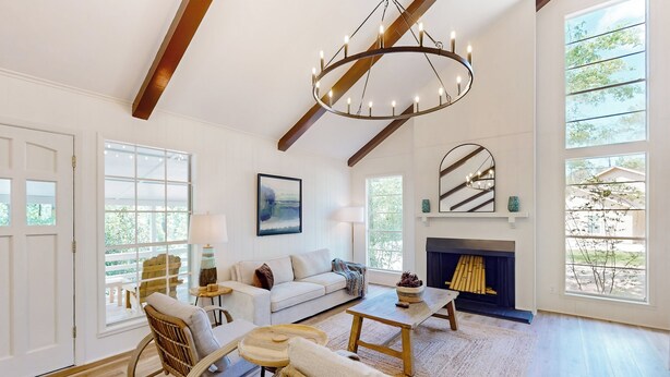 A spacious living room with a fireplace, large windows, and a chandelier. - Modern Treehouse Vibes Close to Club and Lake (Brookeland)