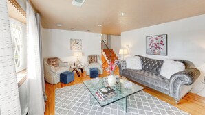 A living room with a sofa, armchairs, a coffee table, and a staircase leading to another level.