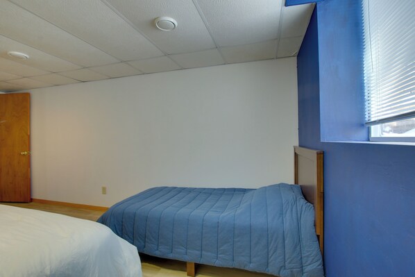 Un dormitorio con una cama individual, una puerta de madera y una ventana con persianas.